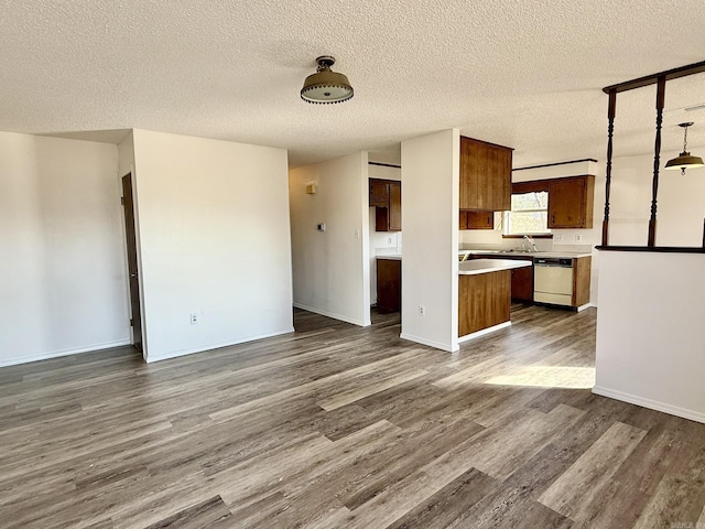 unfurnished living room featuring a sink, dark wood-style floors, baseboards, and a textured ceiling