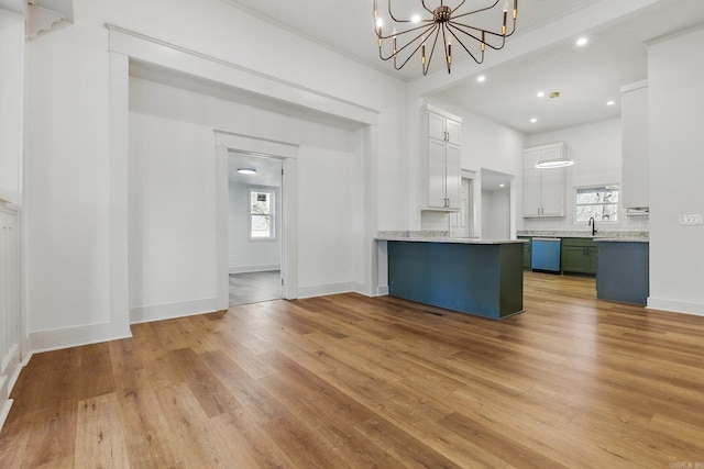 kitchen with a chandelier, light countertops, light wood finished floors, and dishwashing machine