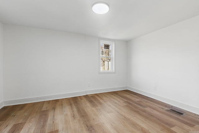 empty room featuring light wood finished floors, visible vents, and baseboards