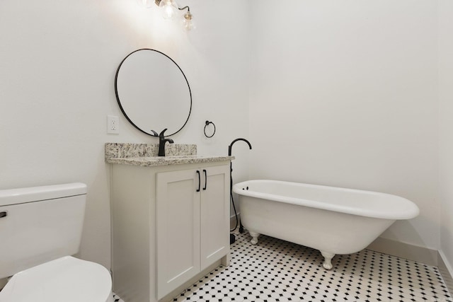 bathroom with a freestanding tub, vanity, toilet, and baseboards