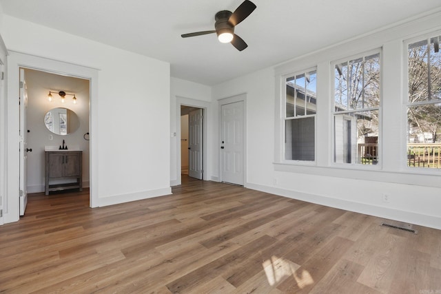 unfurnished bedroom featuring baseboards, ensuite bath, visible vents, and light wood-style floors