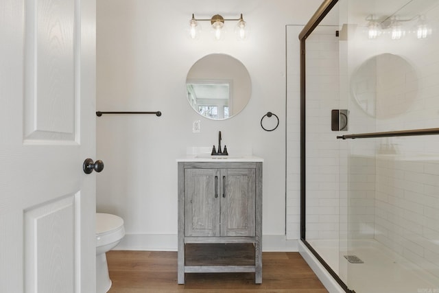 full bathroom with toilet, a stall shower, vanity, wood finished floors, and baseboards