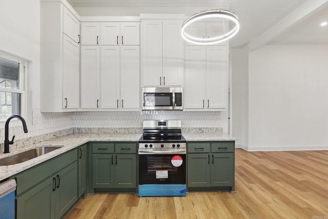 kitchen with stainless steel appliances, a sink, green cabinets, and tasteful backsplash