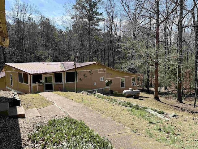 view of front of home featuring metal roof and a forest view