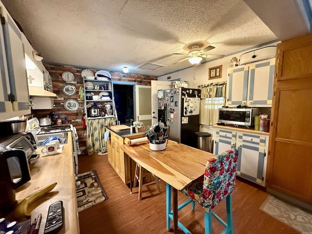 kitchen featuring a textured ceiling, ceiling fan, appliances with stainless steel finishes, and dark wood finished floors