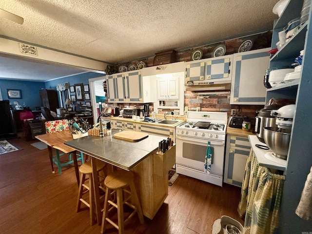 kitchen featuring dark wood finished floors, white gas stove, white cabinets, a sink, and a textured ceiling