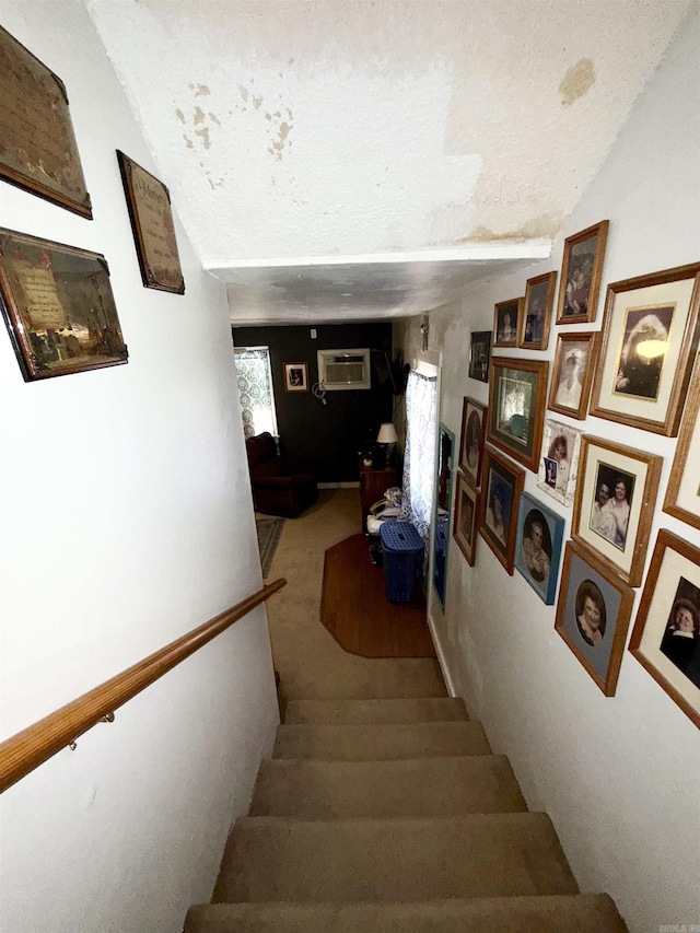 staircase featuring a wall unit AC and a textured ceiling