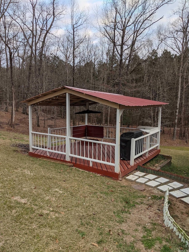 view of front of house with metal roof, a view of trees, and a front lawn