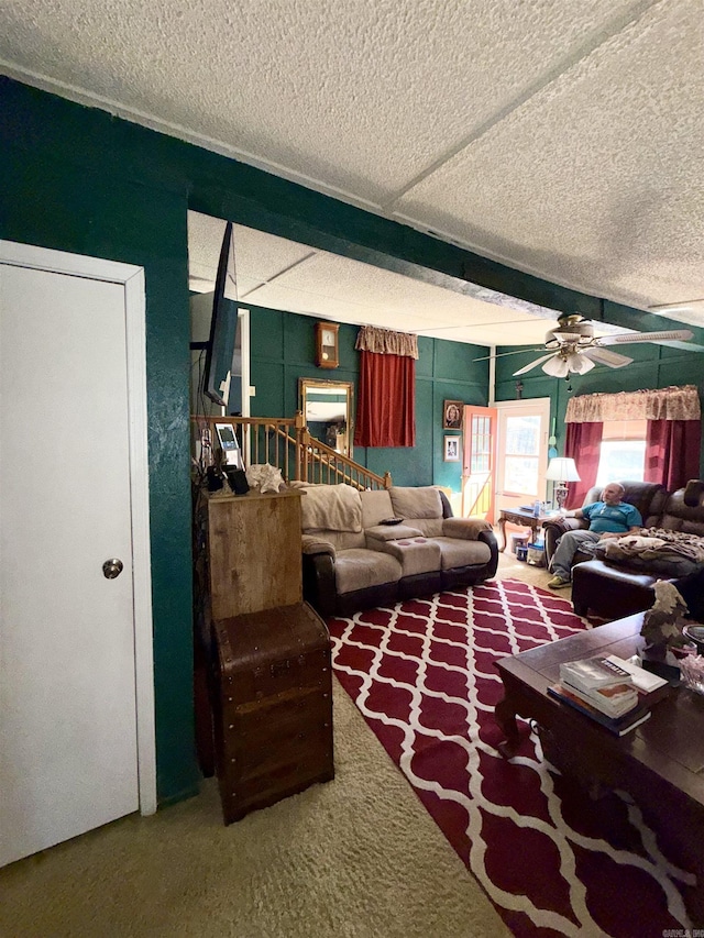 living area featuring carpet floors, ceiling fan, beam ceiling, and a textured ceiling