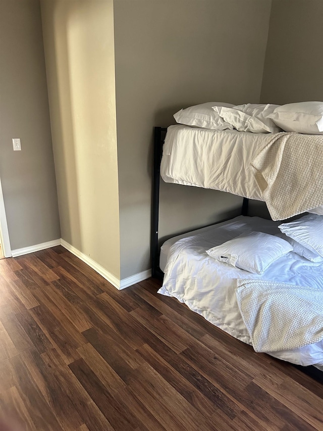 bedroom with baseboards and dark wood-type flooring