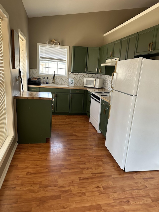 kitchen with a sink, white appliances, backsplash, and green cabinetry