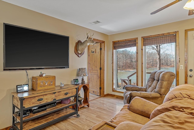 living room with ceiling fan, light wood-style flooring, visible vents, and baseboards