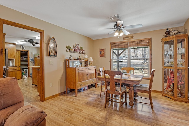 dining area with light wood-style flooring, visible vents, ceiling fan, and baseboards