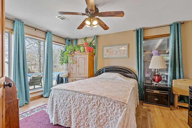 bedroom with access to exterior, a ceiling fan, visible vents, and wood finished floors