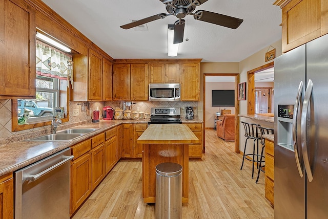 kitchen featuring appliances with stainless steel finishes, light wood-type flooring, a sink, and wood counters