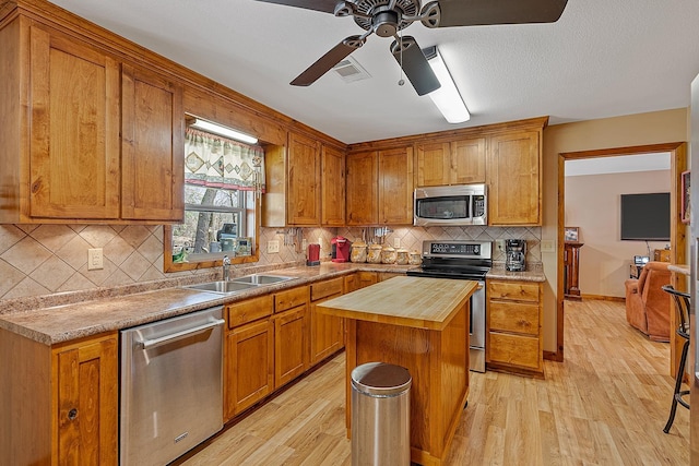 kitchen with light wood-style flooring, appliances with stainless steel finishes, wooden counters, and a sink