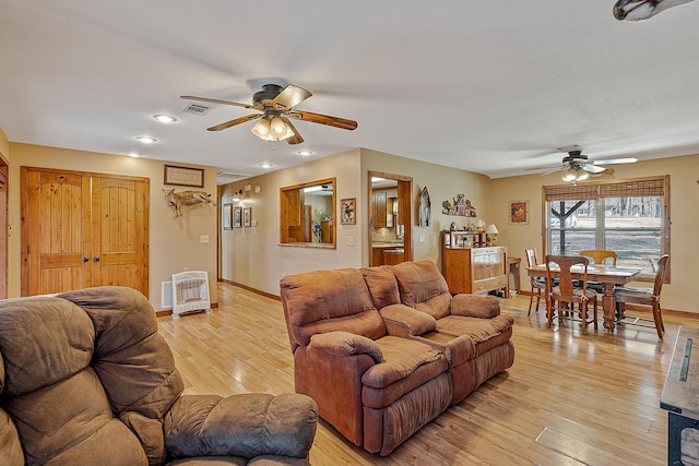 living room featuring ceiling fan, light wood finished floors, visible vents, and baseboards