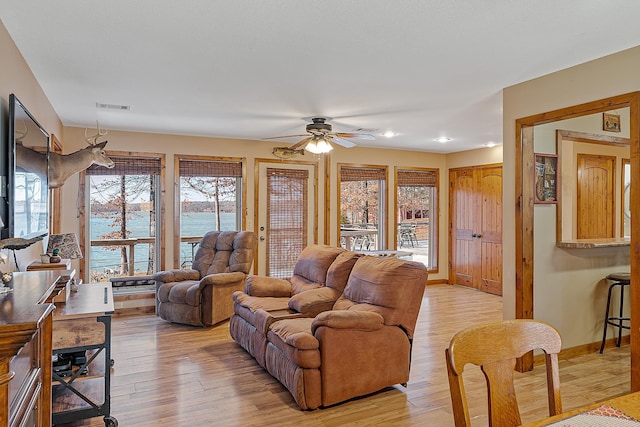 living room with a ceiling fan, light wood-style flooring, visible vents, and baseboards