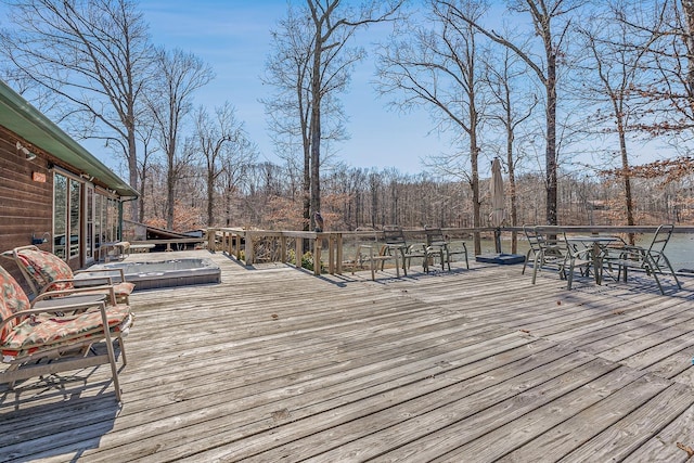 wooden terrace with outdoor dining area and a view of trees