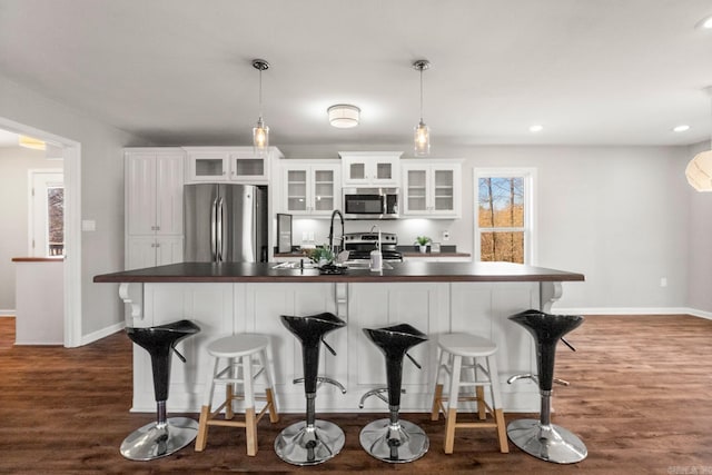 kitchen with stainless steel appliances, dark countertops, and white cabinets