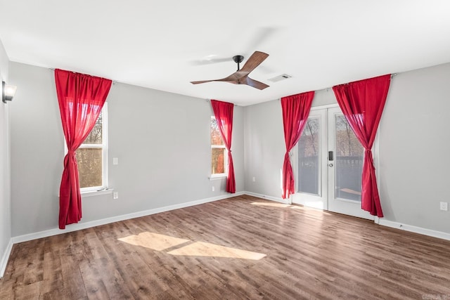 unfurnished room with a ceiling fan, visible vents, baseboards, and wood finished floors