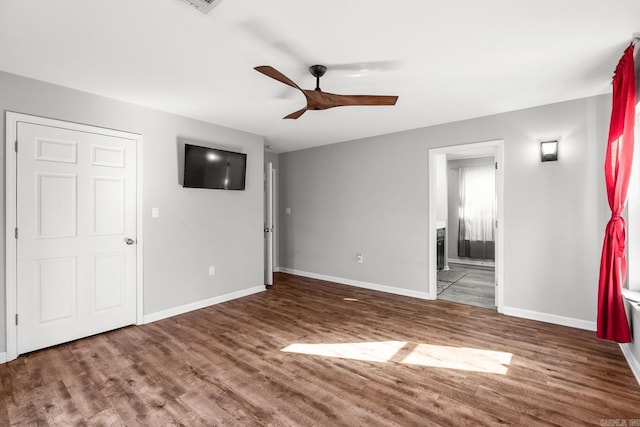 interior space with wood finished floors, a ceiling fan, and baseboards