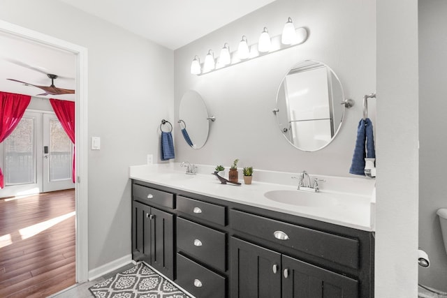 bathroom with ceiling fan, double vanity, wood finished floors, and a sink