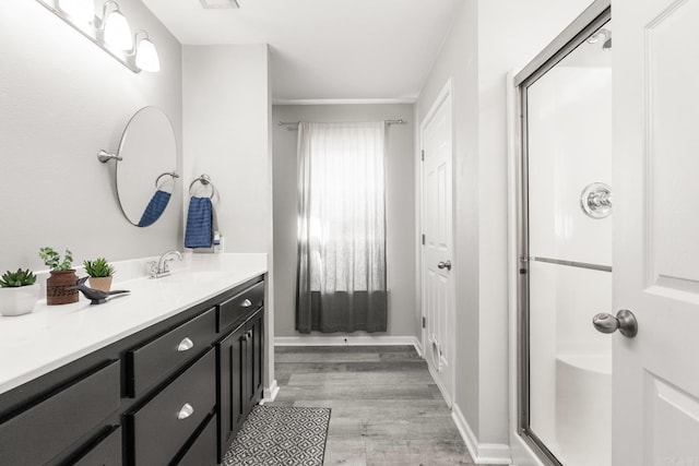 full bathroom with wood finished floors, an enclosed shower, vanity, and baseboards