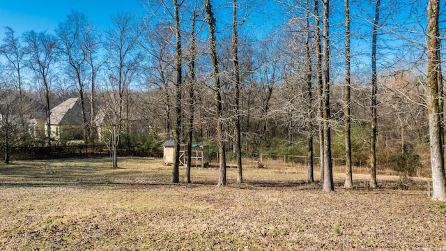 view of yard with a storage shed, a wooded view, and an outdoor structure