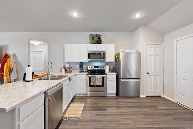 kitchen with a peninsula, white cabinetry, appliances with stainless steel finishes, and a sink