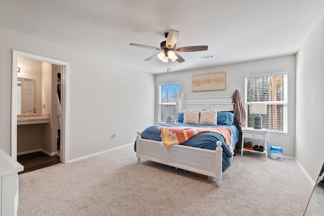 bedroom featuring ensuite bathroom, carpet floors, visible vents, and baseboards