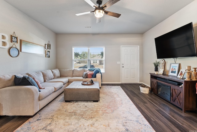 living area featuring baseboards, visible vents, a ceiling fan, and dark wood-type flooring