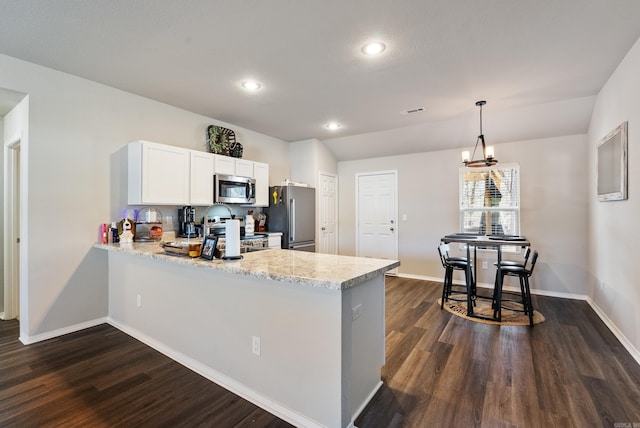 kitchen featuring appliances with stainless steel finishes, dark wood finished floors, a peninsula, and light stone counters