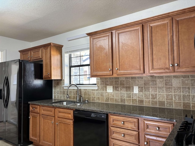 kitchen with a sink, backsplash, dark stone counters, black appliances, and brown cabinetry