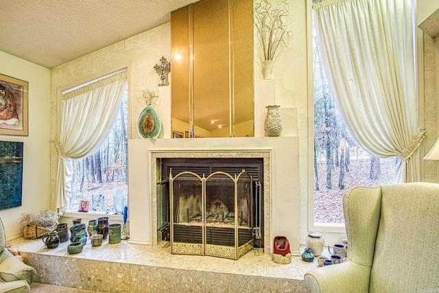 living area featuring a fireplace with raised hearth, a textured ceiling, and a wealth of natural light