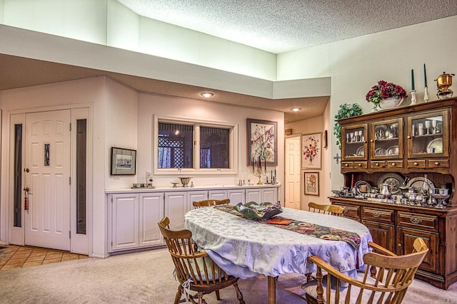 dining space with light carpet, a textured ceiling, and a towering ceiling