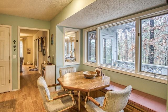 dining room featuring light wood-type flooring and a textured ceiling