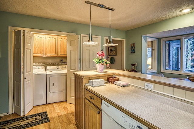 kitchen featuring light countertops, hanging light fixtures, light wood-type flooring, dishwasher, and washer and clothes dryer