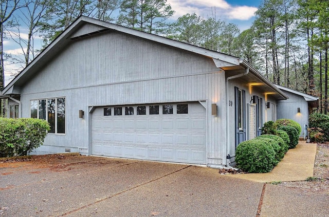 view of property exterior with crawl space, a garage, and concrete driveway