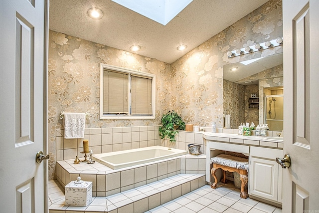 full bathroom featuring a textured ceiling, a garden tub, tile patterned flooring, a skylight, and wallpapered walls