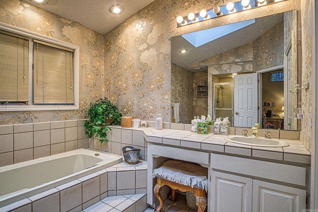 bathroom with a garden tub, lofted ceiling with skylight, a shower stall, vanity, and wallpapered walls