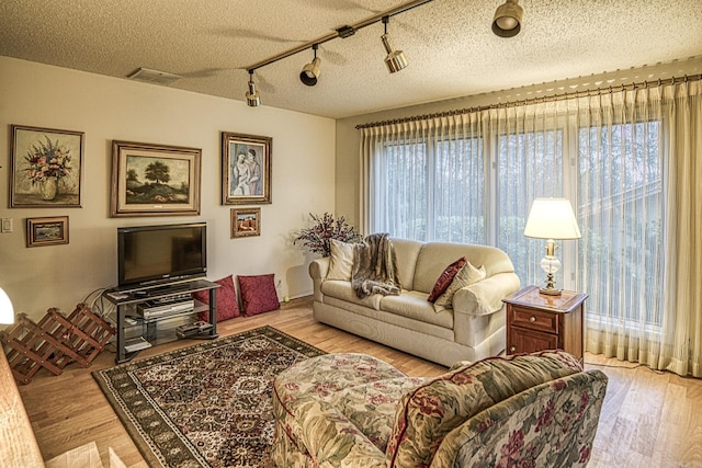 living area with a textured ceiling, wood finished floors, and visible vents