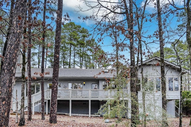 back of property with stairs, a deck, and roof with shingles