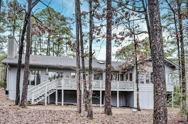 rear view of house featuring a deck, a chimney, and stairs