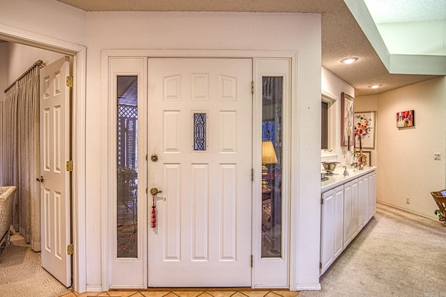 entrance foyer with light carpet, a textured ceiling, and recessed lighting