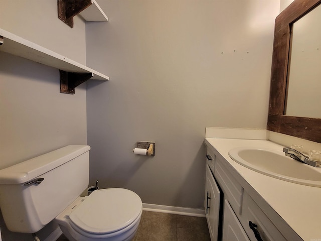 half bathroom with baseboards, vanity, toilet, and tile patterned floors