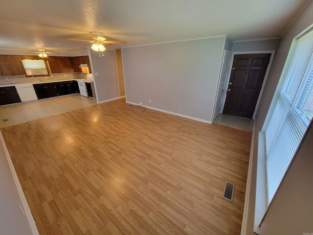 unfurnished living room featuring a textured ceiling, a ceiling fan, baseboards, light wood-style floors, and ornamental molding