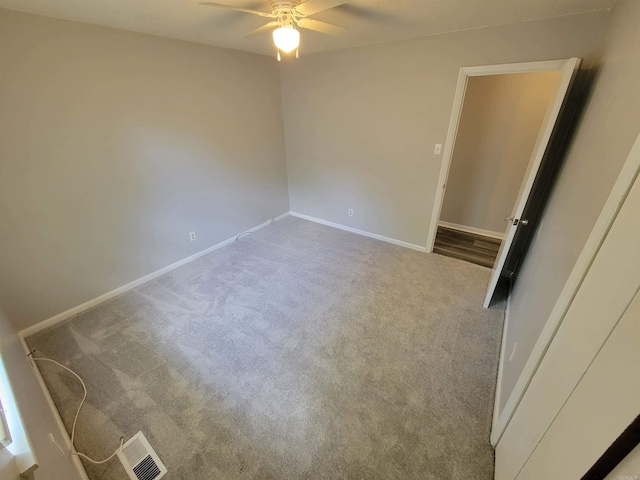 spare room featuring carpet floors, a ceiling fan, visible vents, and baseboards