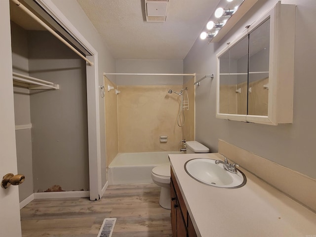 bathroom featuring wood finished floors, toilet, a textured ceiling, shower / tub combination, and vanity