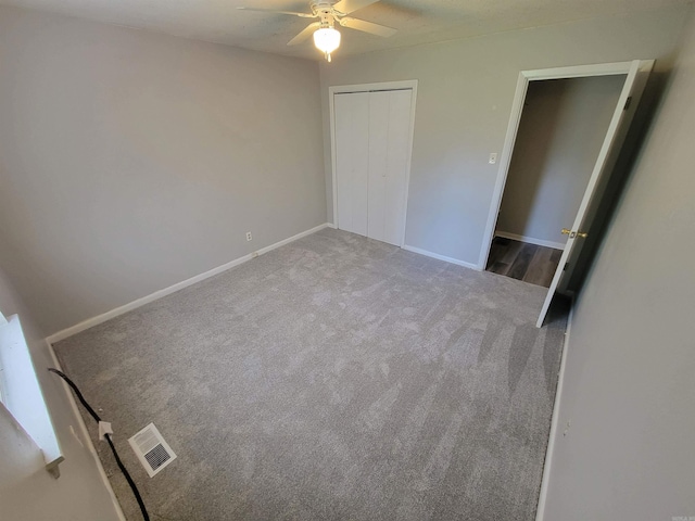 unfurnished bedroom with carpet floors, visible vents, a ceiling fan, baseboards, and a closet